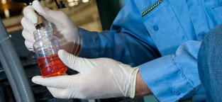 Worker in rubber gloves holding bottle of red liquid